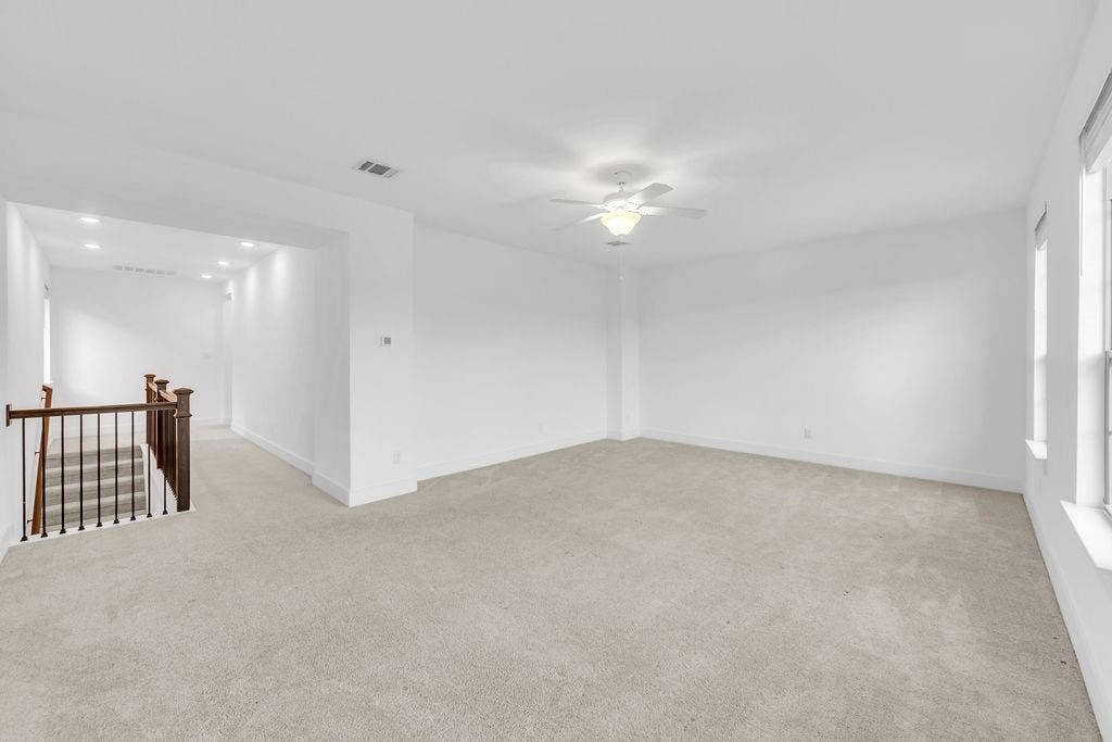 8300 Bethpage Drive, McKinney, TX 75070 Expansive carpeted area with bright neutral walls and a ceiling fan