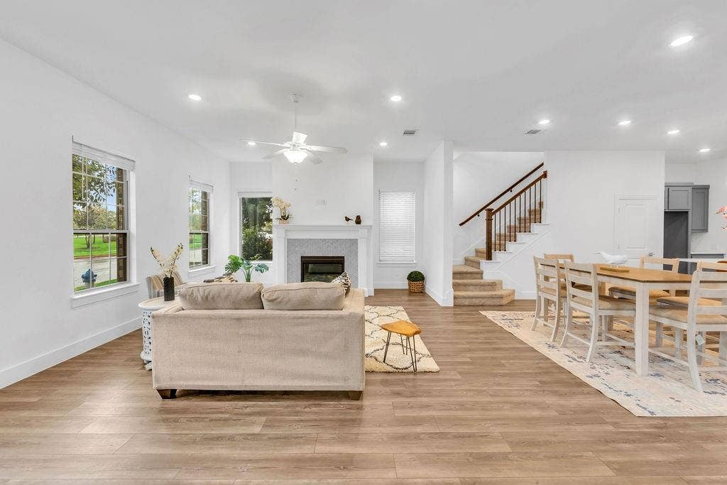 8300 Bethpage Drive, McKinney, TX 75070 Wood-finish flooring throughout, white walls, recessed lighting, fireplace with mantel, and a staircase with wood handrails