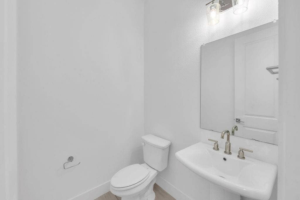 8300 Bethpage Drive, McKinney, TX 75070 Pedestal sink with a brushed nickel faucet, wall-mounted mirror, and overhead vanity lighting