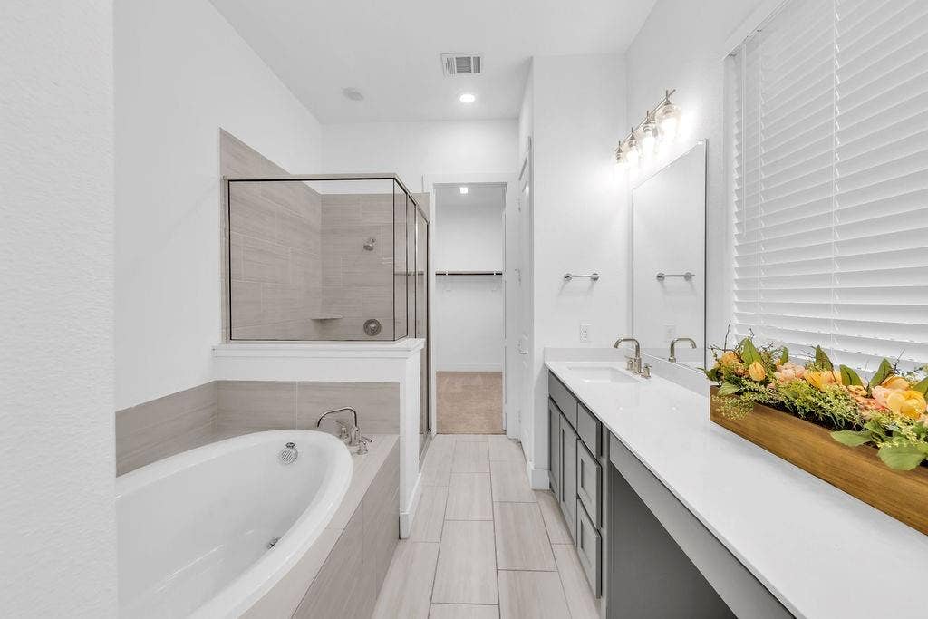 8300 Bethpage Drive, McKinney, TX 75070 Dual vanity with undermount sinks, a built-in bathtub, a walk-in shower with glass enclosure, and light-toned tile flooring