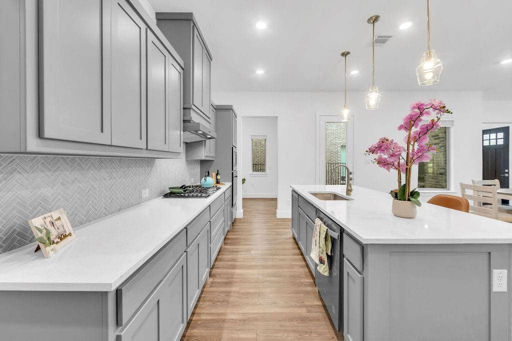8300 Bethpage Drive, McKinney, TX 75070 Light gray cabinetry with a herringbone tile backsplash, white countertops, and wood-finish flooring