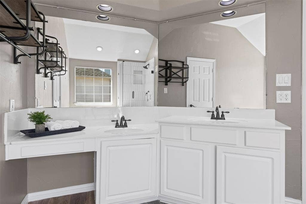 5401 Wolcott Place, Richardson, TX 75082 Dual vanity with white cabinetry, integrated sinks, black finish faucets, and a full-width mirror