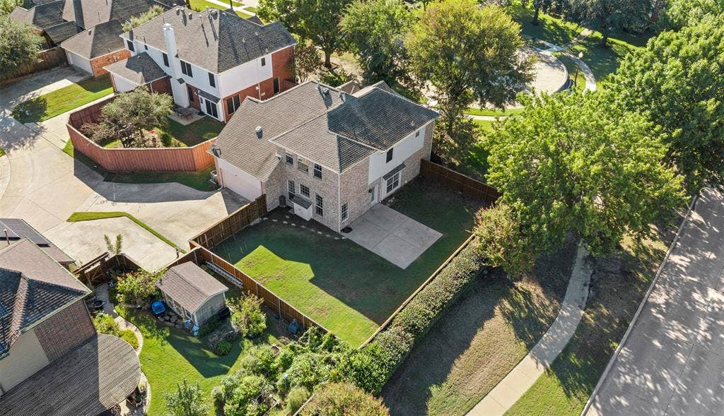 5401 Wolcott Place, Richardson, TX 75082 Two-story residence with a brick and siding exterior, an attached two-car garage, a fenced backyard with a patio, and a separate storage shed