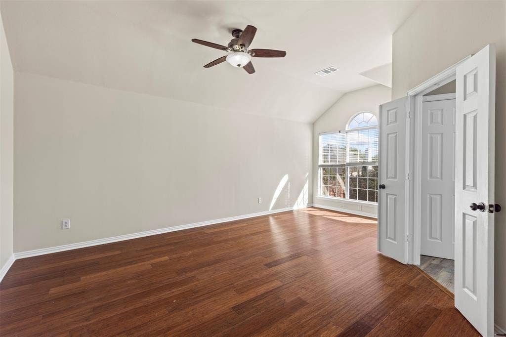 5401 Wolcott Place, Richardson, TX 75082 Wood-finish flooring, vaulted ceiling, arched window, ceiling fan, and white panel doors