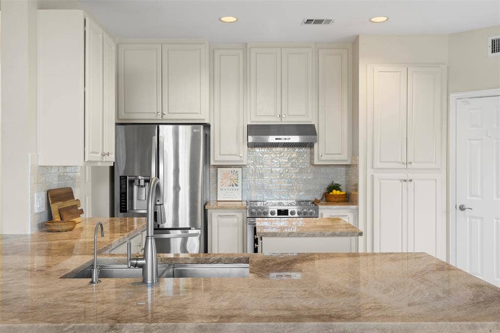 5401 Wolcott Place, Richardson, TX 75082 Kitchen featuring light-toned cabinetry, stainless steel appliances, a range with an overhead exhaust, and a tiled backsplash