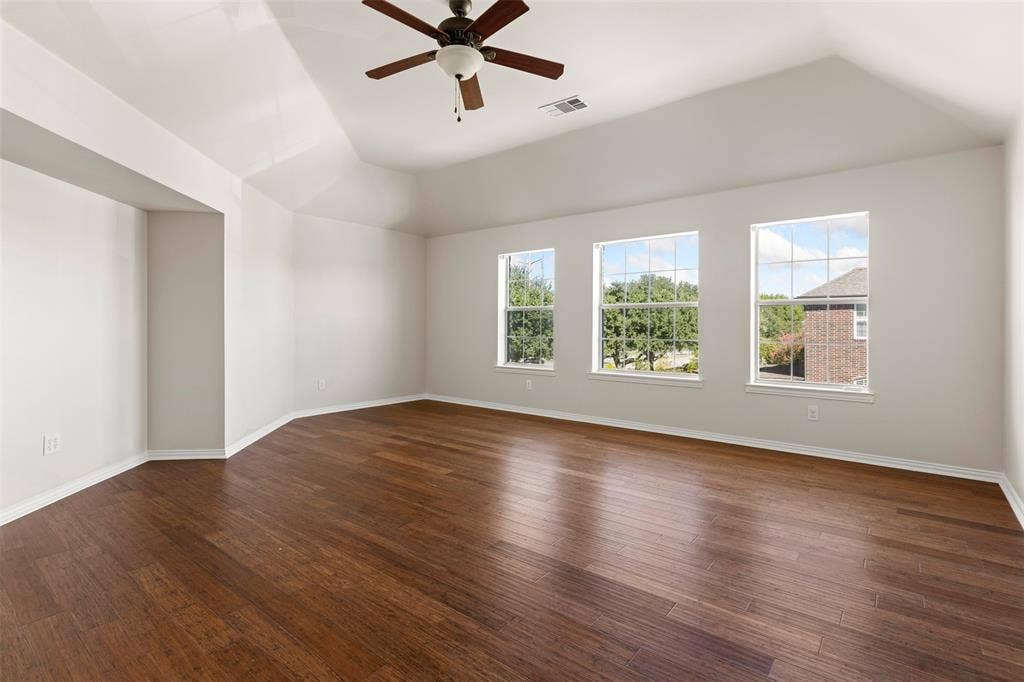 5401 Wolcott Place, Richardson, TX 75082 Vaulted ceiling with a ceiling fan, three windows, wood-finish flooring, and white painted walls