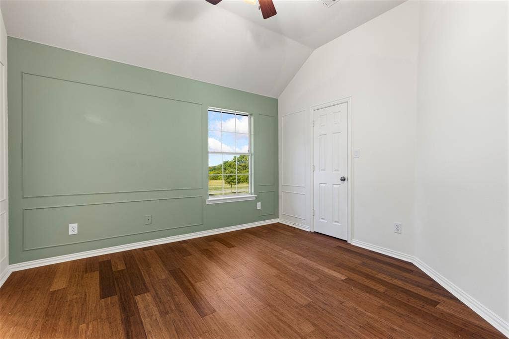 5401 Wolcott Place, Richardson, TX 75082 Vaulted ceiling, wood-finish flooring, accent wall with decorative trim, paneled door, ceiling fan