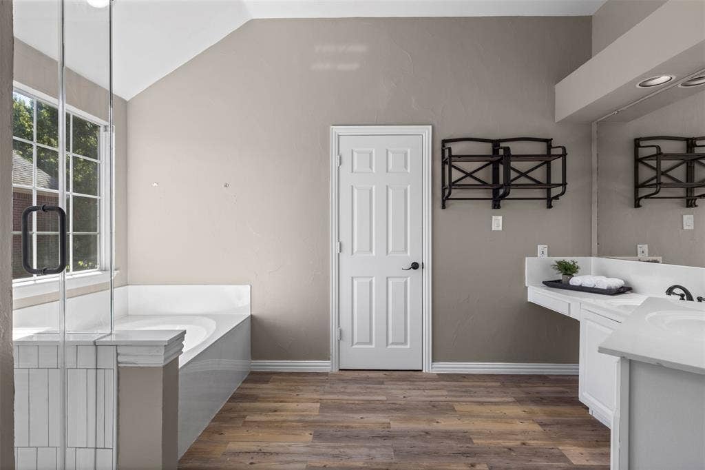 5401 Wolcott Place, Richardson, TX 75082 Soaking tub with a tiled surround, glass-enclosed shower, wood-finish flooring, dual vanity with undermount sinks, and recessed lighting