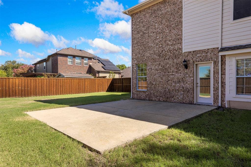 5401 Wolcott Place, Richardson, TX 75082 Expansive concrete patio with a manicured lawn, brick and siding exterior, and a privacy fence