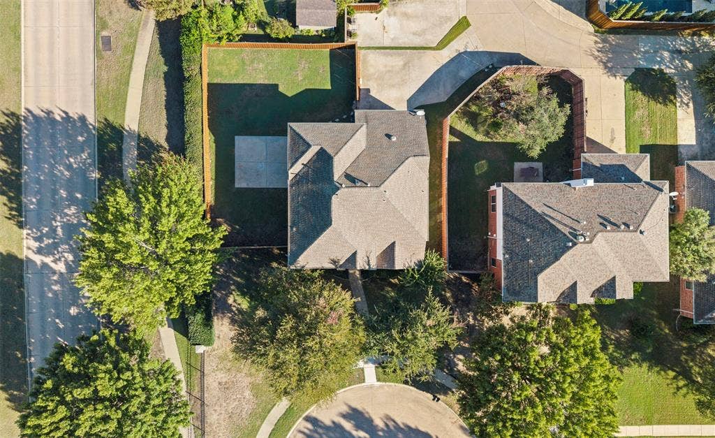5401 Wolcott Place, Richardson, TX 75082 Pitched roof architecture, paved driveway, landscaped yard, concrete patio, and mature perimeter trees