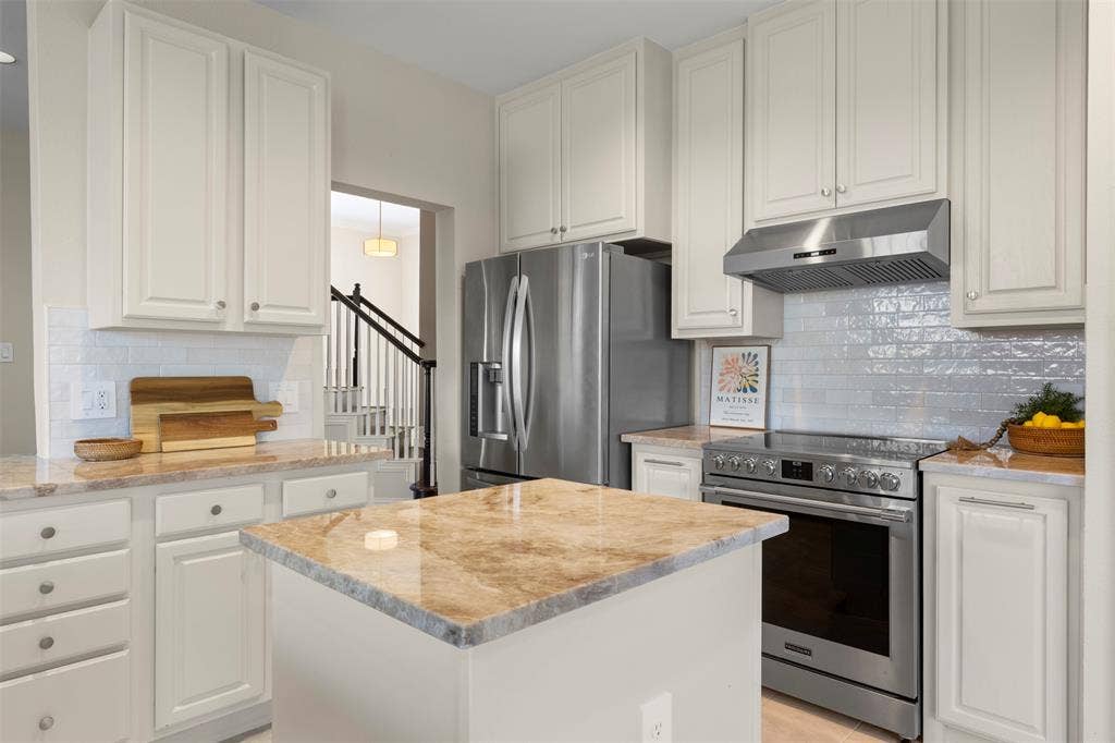 5401 Wolcott Place, Richardson, TX 75082 Kitchen featuring white cabinetry, stainless steel appliances, a tile backsplash, light-toned countertops, and a central island