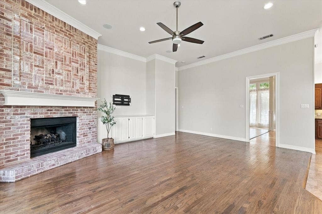 Wood-finish flooring, brick-clad fireplace with mantel, built-in cabinetry, recessed lighting, and ceiling fan