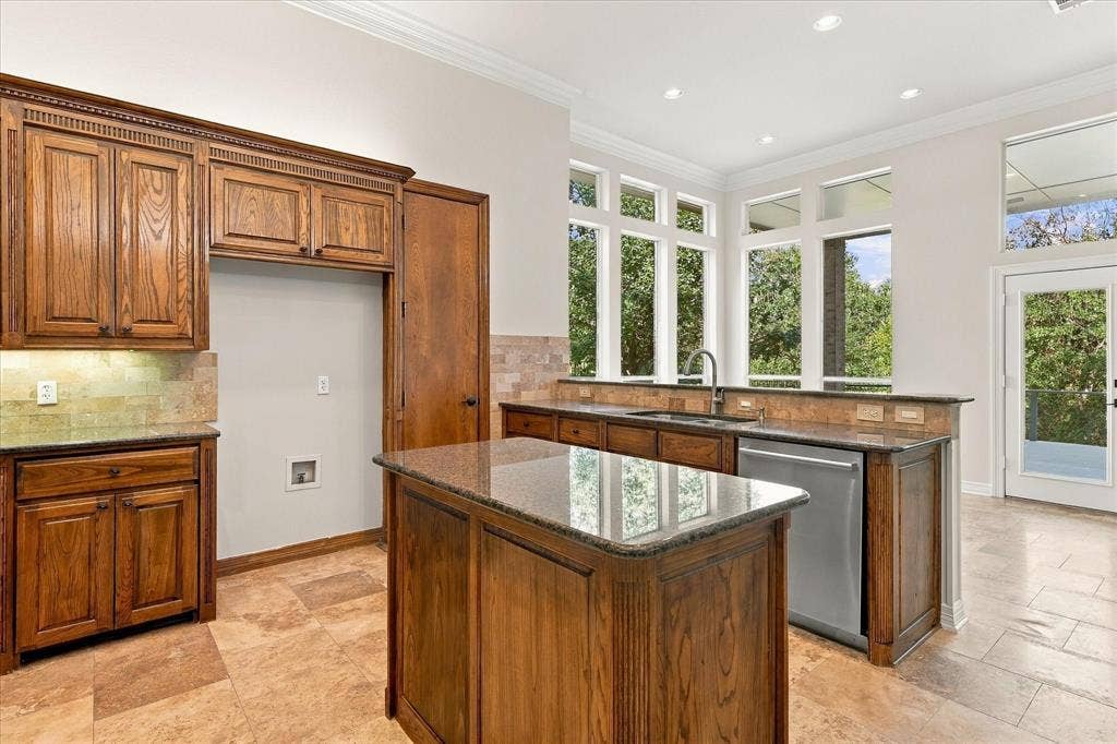 Expansive windows, crown molding, a built-in dishwasher, an integrated kitchen island, and tiled flooring