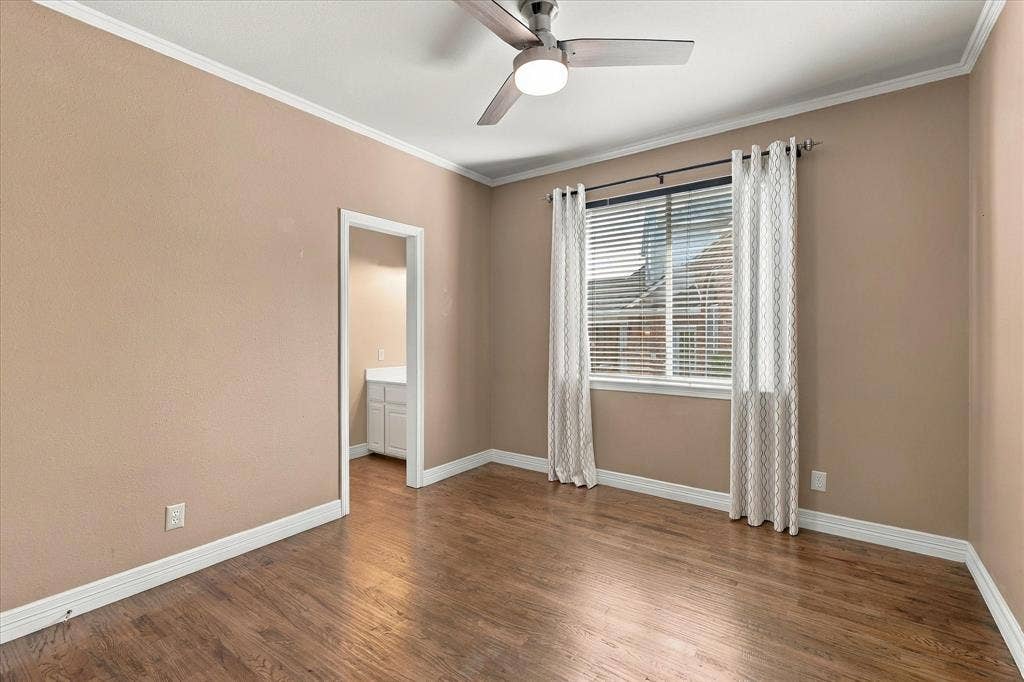 Hardwood-style flooring with a natural finish, white crown molding, and a ceiling fan with integrated lighting
