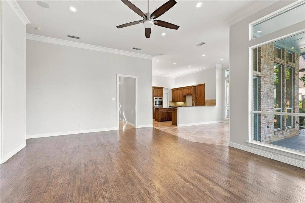 Hardwood flooring, crown molding, ceiling fan, recessed lighting, and large windows