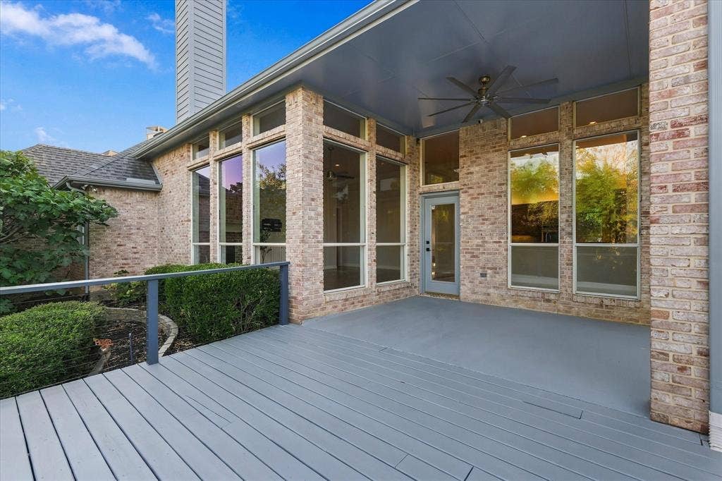 Expansive outdoor decking, brick exterior, large picture windows, covered patio, and ceiling fan