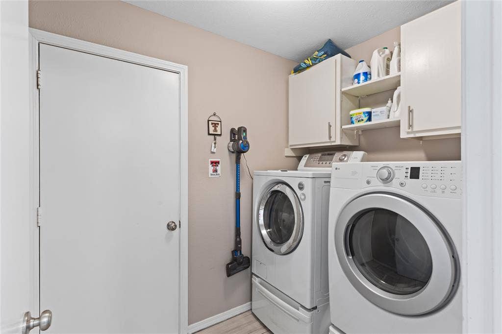 Integrated laundry area with upper cabinetry and open shelving