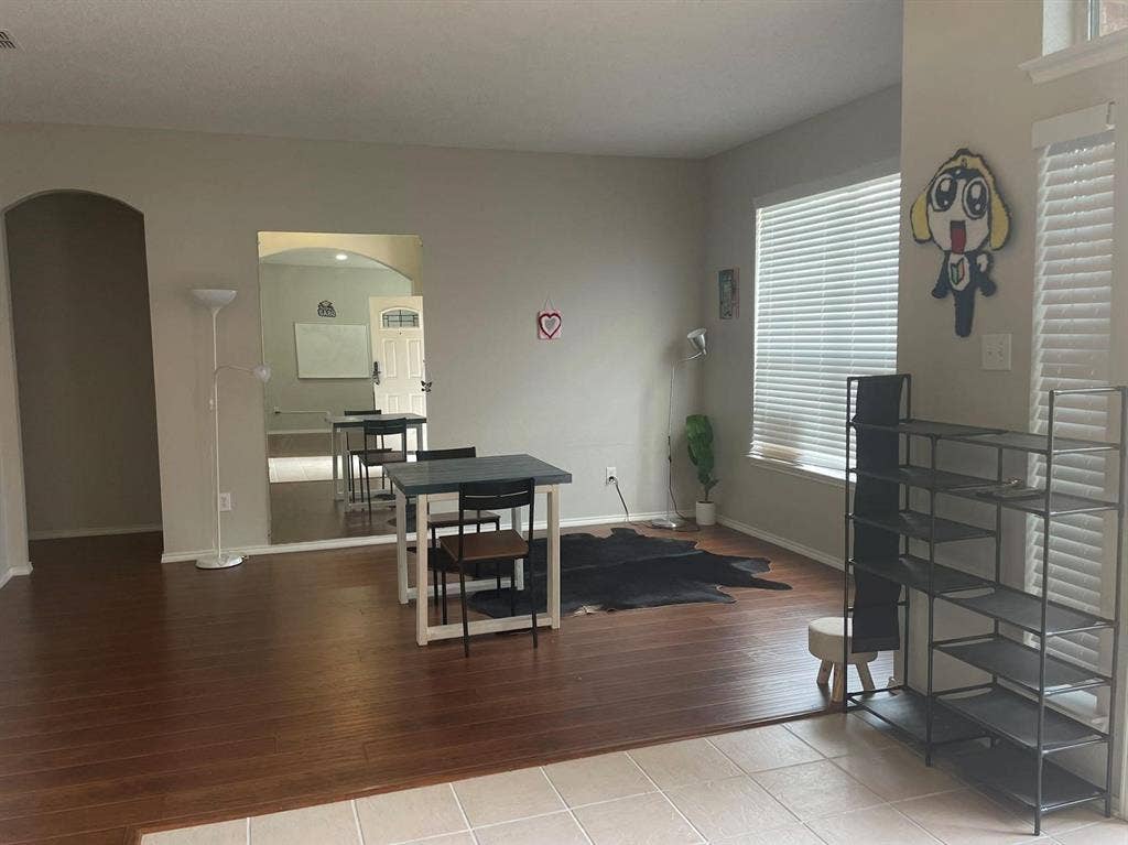 Living area featuring wood-finish flooring, neutral wall paint, arched entryways, and windows with horizontal blinds