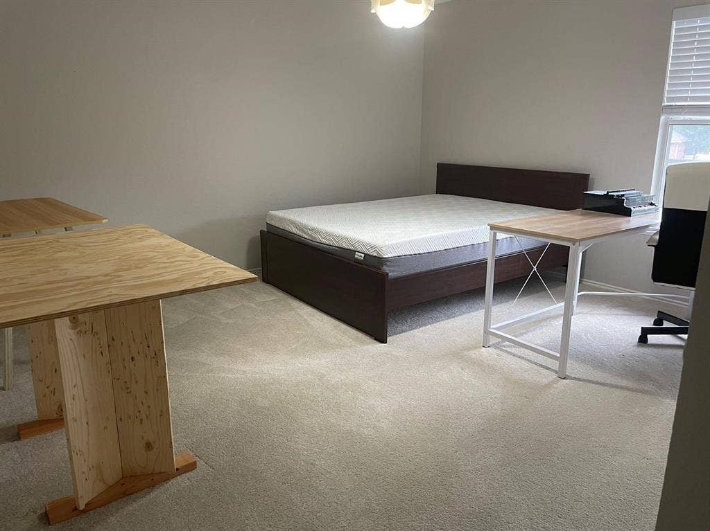Neutral-toned interior room featuring wall-to-wall carpeting and a window with horizontal blinds