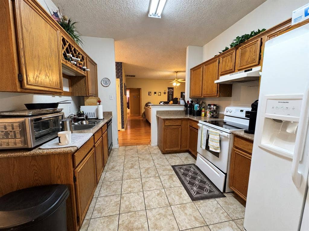 725 Andalusia Trail, DeSoto, TX 75115 U-shaped kitchen featuring wood cabinetry, stone-finish countertops, tile flooring, and integrated wine storage