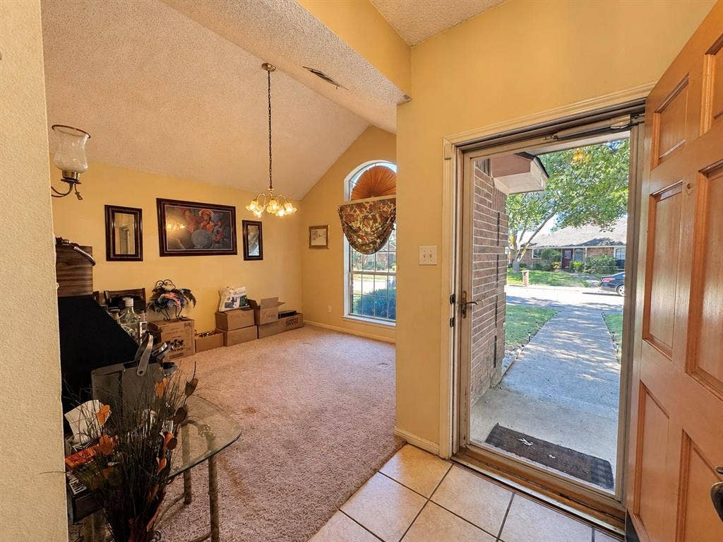 725 Andalusia Trail, DeSoto, TX 75115 Vaulted ceiling, chandelier lighting, arched window, wood paneled door, and tile flooring at entrance