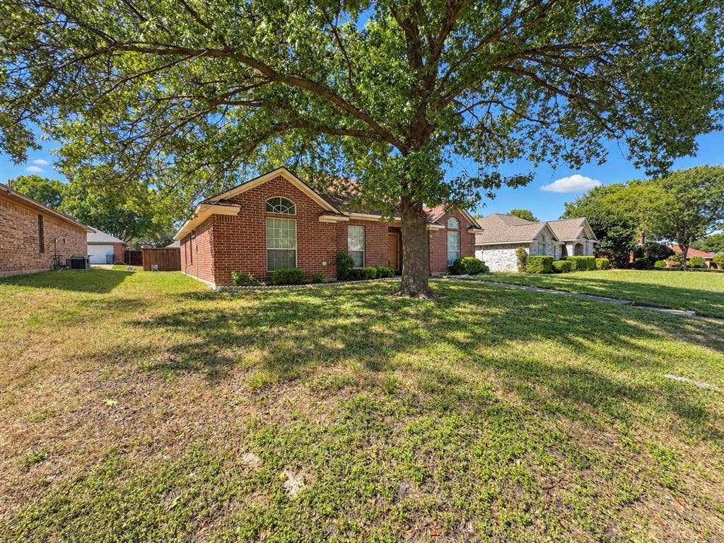 725 Andalusia Trail, DeSoto, TX 75115 Brick-clad exterior with an arched window, a mature shade tree, and a pitched roof