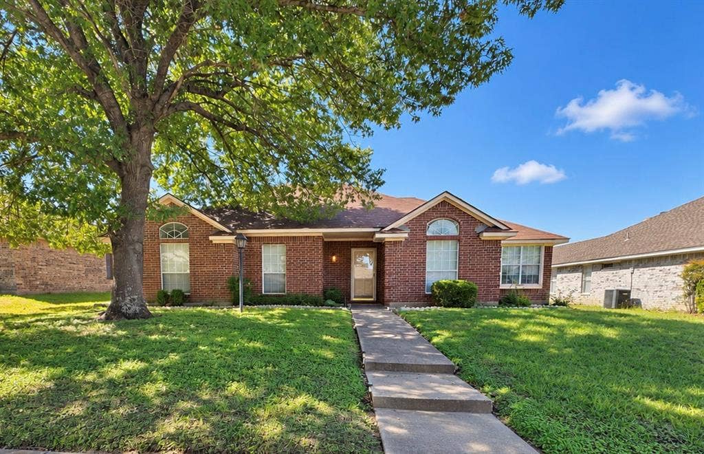 725 Andalusia Trail, DeSoto, TX 75115 Brick-clad exterior with a concrete walkway, arched window, and mature tree