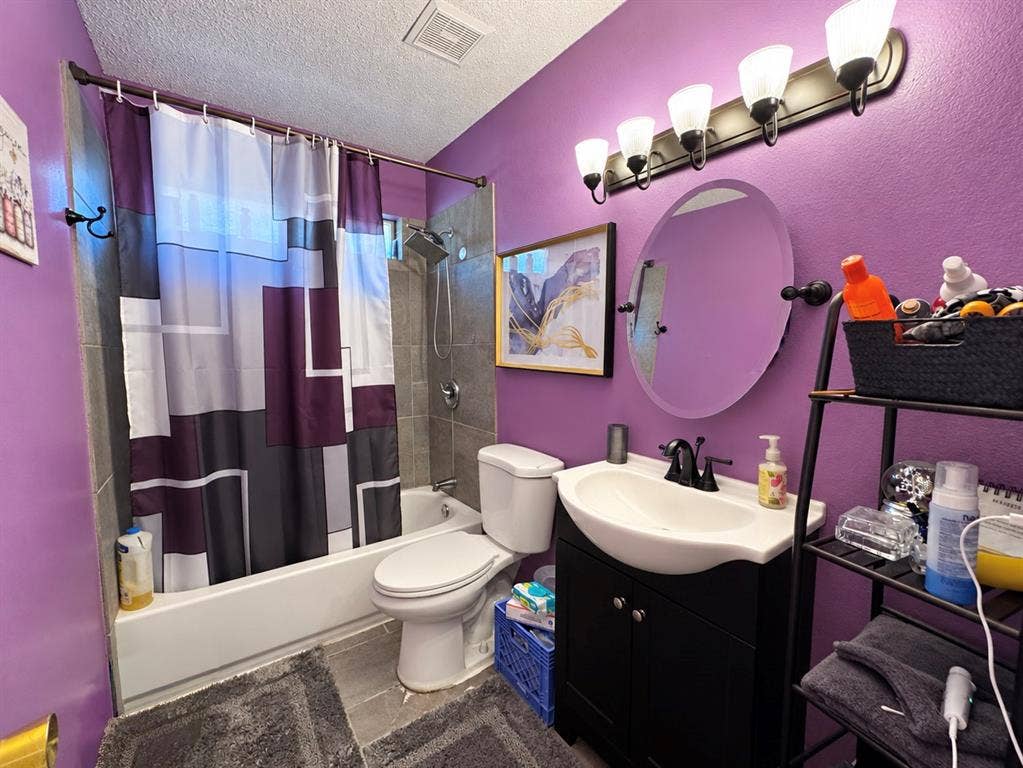 725 Andalusia Trail, DeSoto, TX 75115 Bathtub with tile surround, a built-in toilet, and a vanity with an integrated sink and black faucet