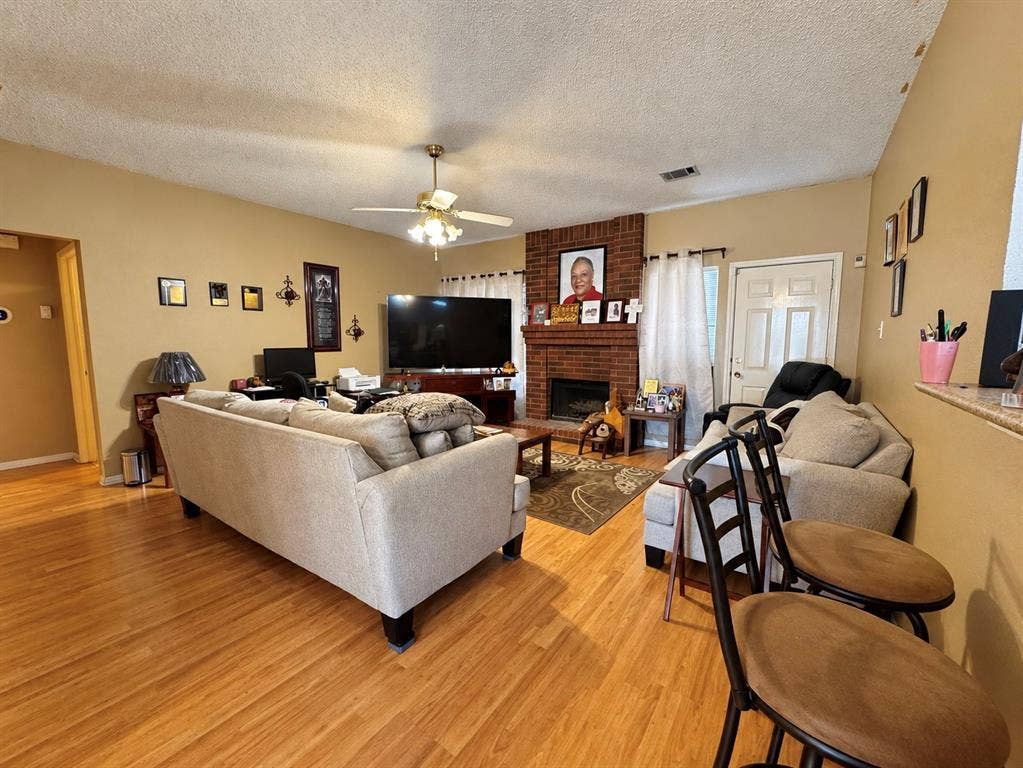 725 Andalusia Trail, DeSoto, TX 75115 Wood-finish flooring throughout, brick-surround fireplace, ceiling fan with integrated lighting, and a white paneled door