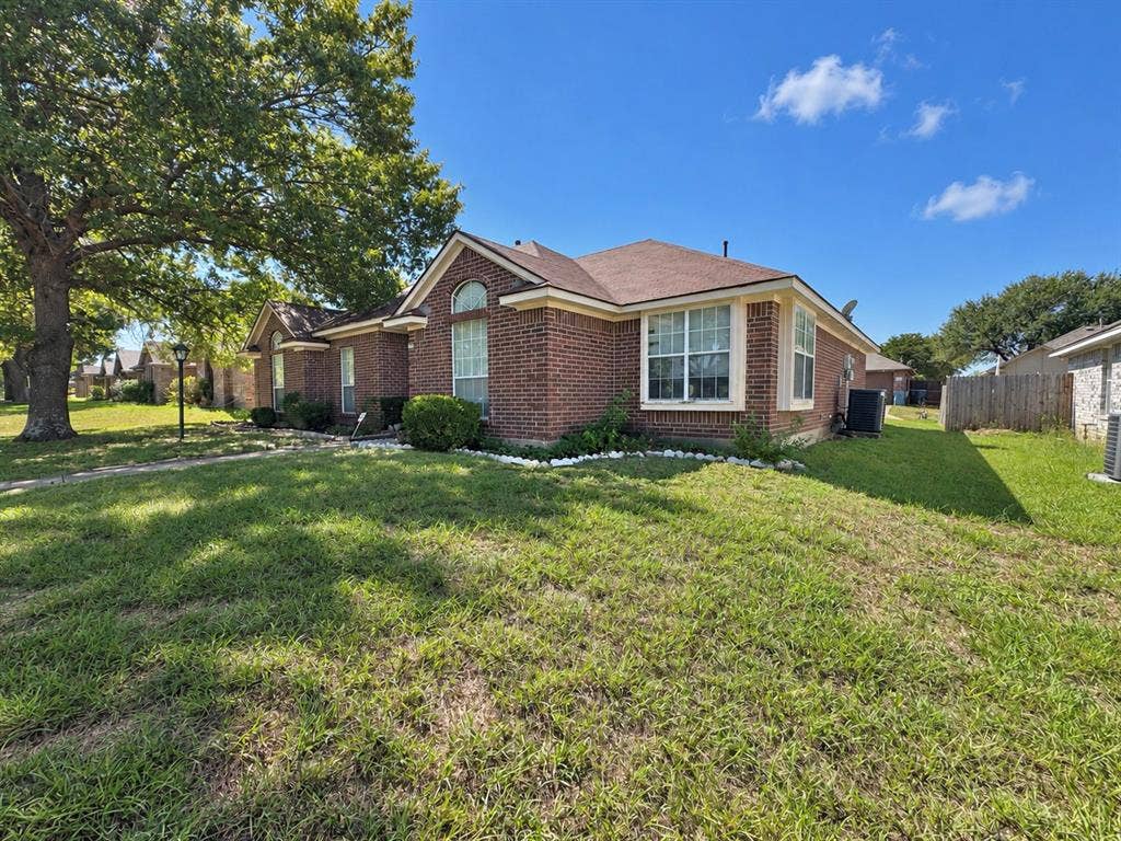 725 Andalusia Trail, DeSoto, TX 75115 Brick exterior with arched window details, multiple pane windows, and a mature tree
