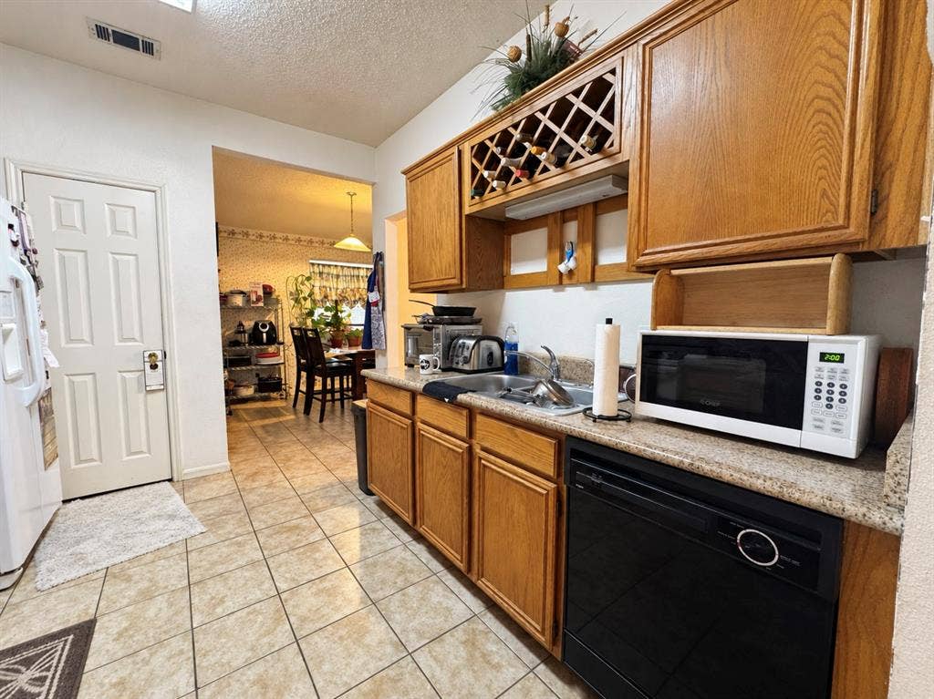725 Andalusia Trail, DeSoto, TX 75115 Kitchen featuring wood cabinetry, integrated wine rack, and a black dishwasher