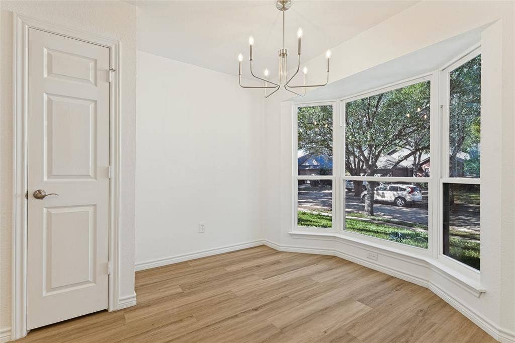 7440 Bear Lake Drive, Fort Worth, TX 76137 Bay window with exterior scenery, wood-finish flooring, contemporary chandelier, and a paneled interior door