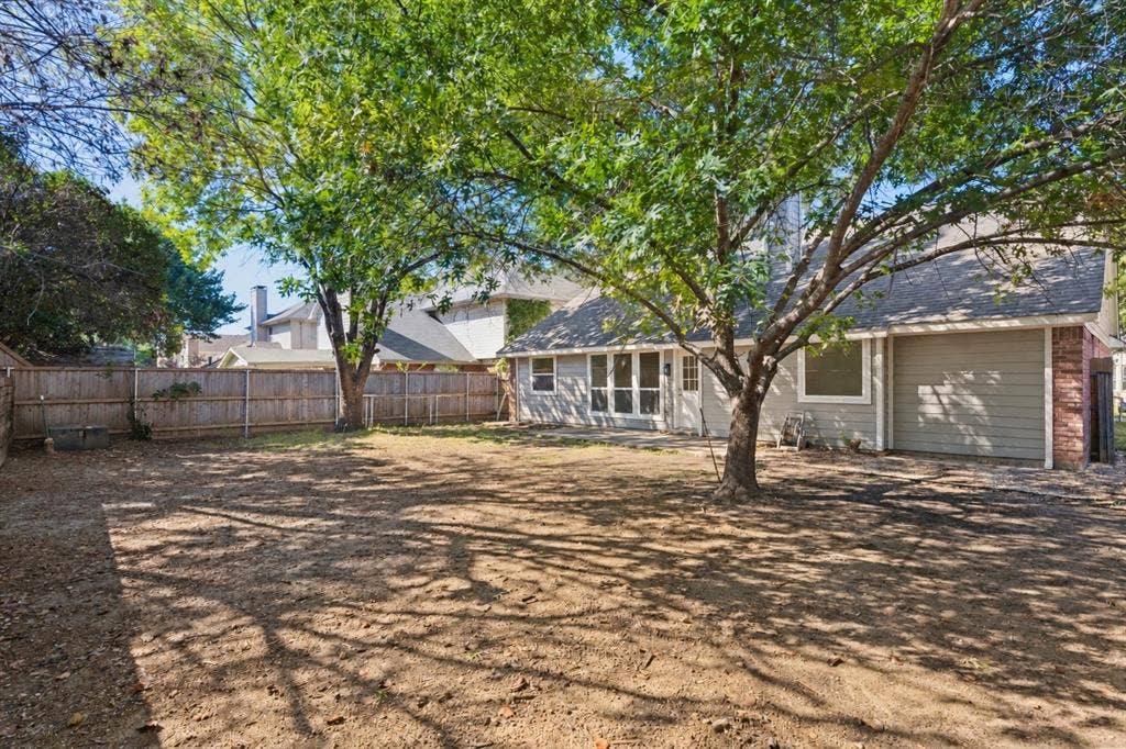 7440 Bear Lake Drive, Fort Worth, TX 76137 Spacious backyard with mature trees, wood fence, and a screened-in porch