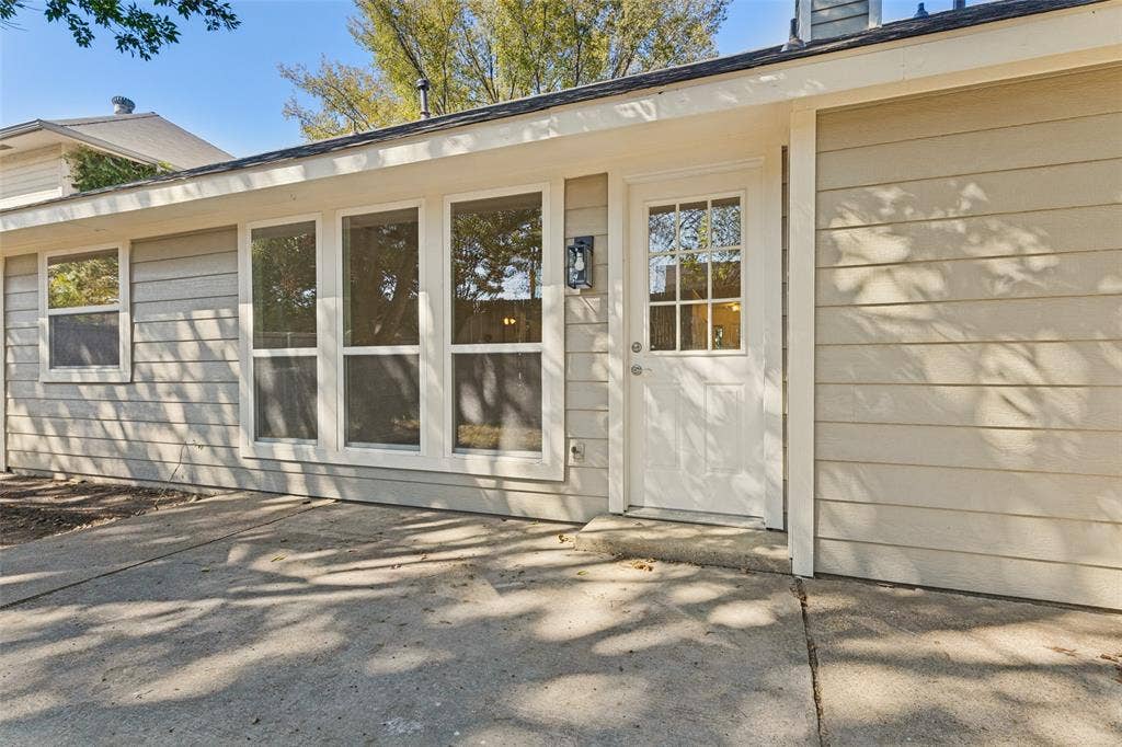 7440 Bear Lake Drive, Fort Worth, TX 76137 Exterior siding in a neutral tone, multiple windows, and a glass-paneled door