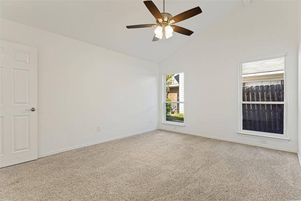 7440 Bear Lake Drive, Fort Worth, TX 76137 Vaulted ceiling, ceiling fan with light fixture, two windows, carpet flooring, and a paneled door