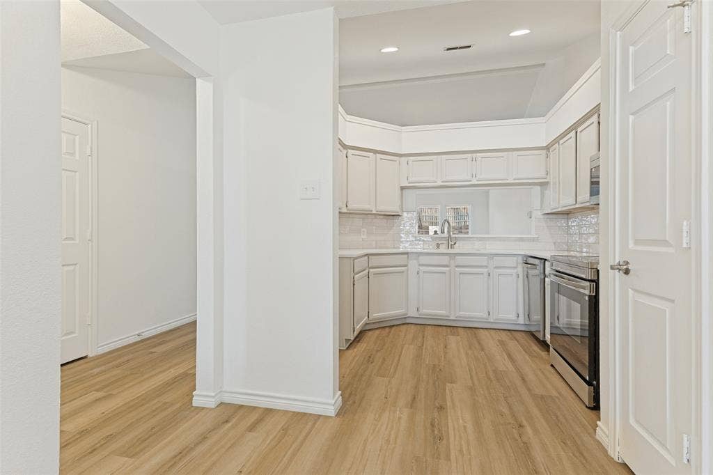 7440 Bear Lake Drive, Fort Worth, TX 76137 Kitchen featuring light wood-finish flooring, white cabinetry, integrated stainless steel appliances, a tile backsplash, and recessed lighting