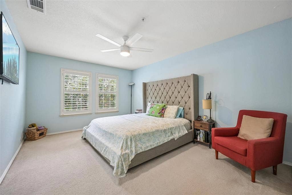 2209 Stonepark Place, McKinney, TX 75071 Wall-mounted television, two windows with plantation shutters, ceiling fan with integrated lighting, and carpet flooring
