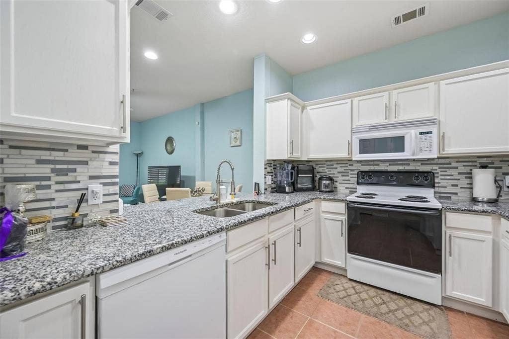 2209 Stonepark Place, McKinney, TX 75071 White cabinetry, granite-style countertops, mosaic tile backsplash, stainless steel sink, and recessed lighting