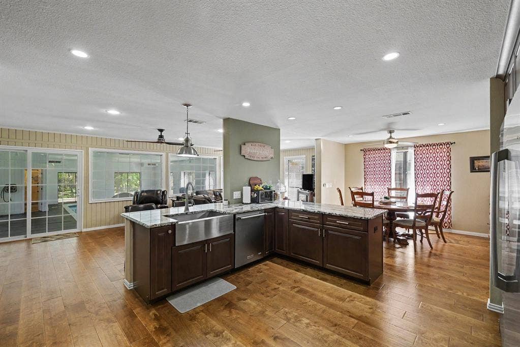 26 Brookhaven Drive, Lucas, TX 75002 Kitchen island with an undermount farmhouse sink, granite countertops, and dark wood-finish cabinetry