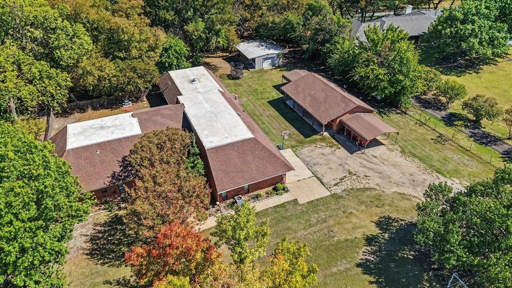 26 Brookhaven Drive, Lucas, TX 75002 Expansive property featuring multiple structures, mature trees, a paved driveway, and an additional covered car port