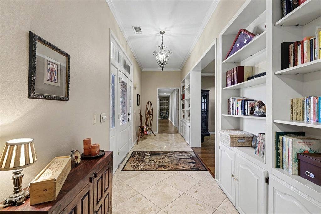 26 Brookhaven Drive, Lucas, TX 75002 Hallway featuring tile flooring, built-in shelving, white paneled doors, and a decorative chandelier