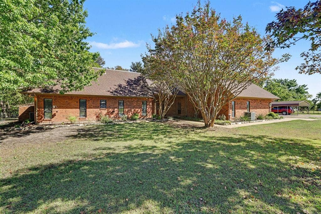 26 Brookhaven Drive, Lucas, TX 75002 Brick exterior with a shingle roof, mature landscaping, and an attached carport