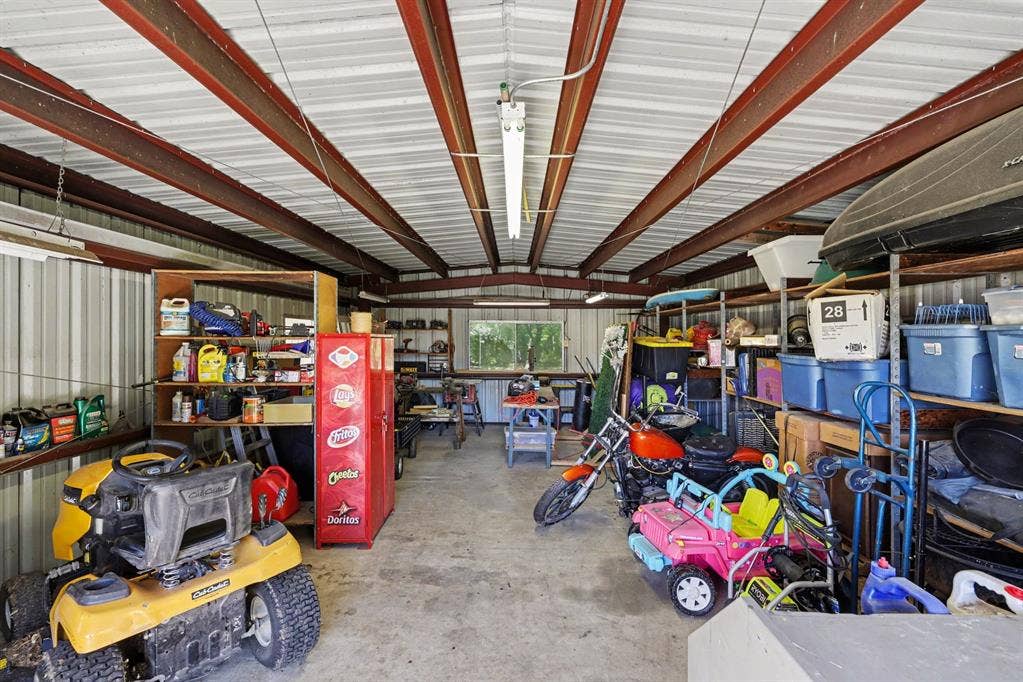 26 Brookhaven Drive, Lucas, TX 75002 Metal-clad structure with exposed steel beam ceiling, concrete flooring, built-in shelving, and transom window