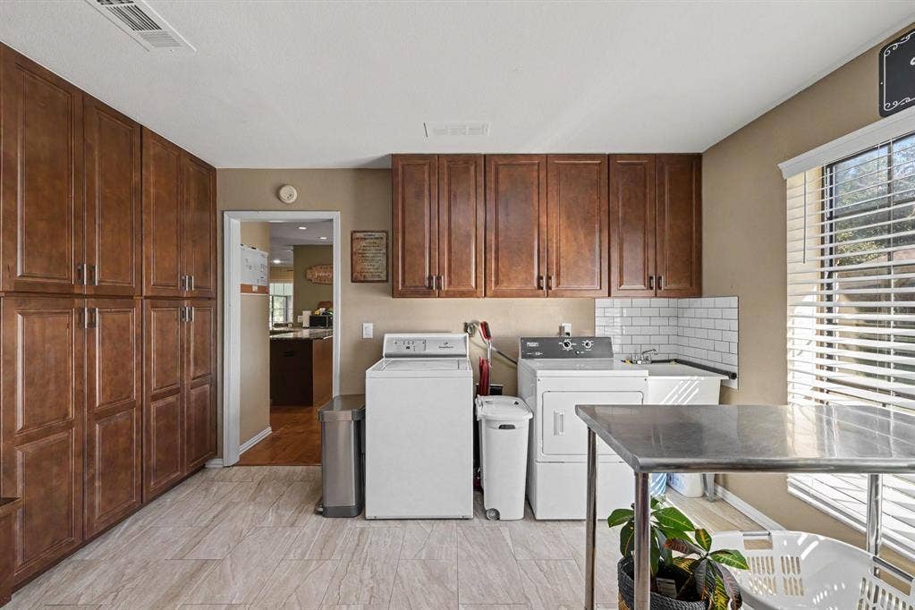 26 Brookhaven Drive, Lucas, TX 75002 Dedicated utility room featuring extensive built-in cabinetry, ceramic tile flooring, a utility sink with subway tile backsplash, and a window with blinds