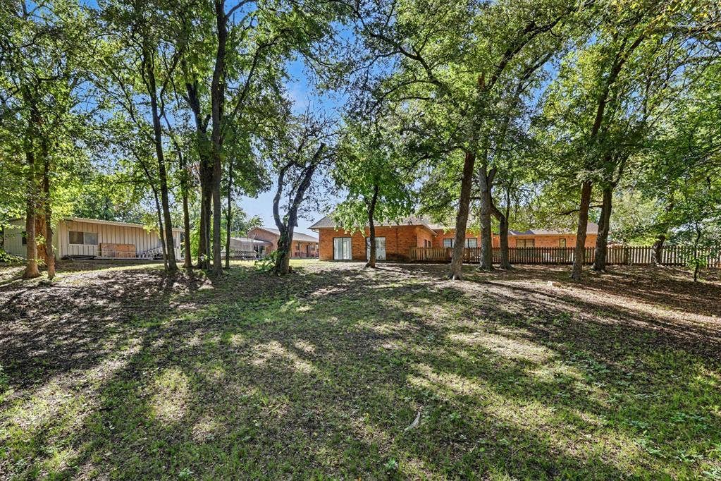 26 Brookhaven Drive, Lucas, TX 75002 Expansive grassy yard with mature trees, a wood deck, and a wood fence