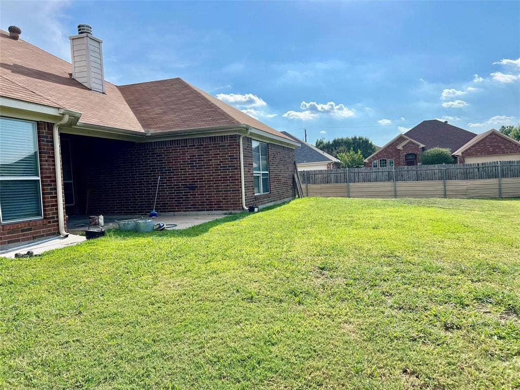 1801 Kathryn Court, Arlington, TX 76018 Expansive backyard featuring a manicured lawn, brick exterior, covered patio, and privacy fencing