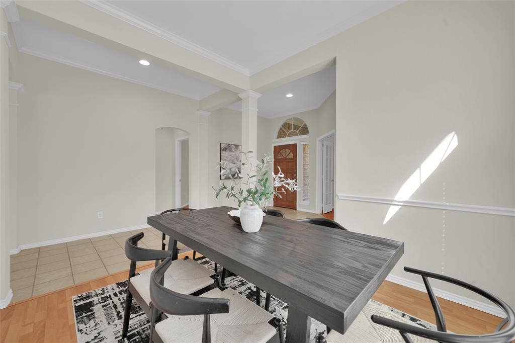 Recessed lighting illuminates the dining area, featuring crown molding and chair rail detailing