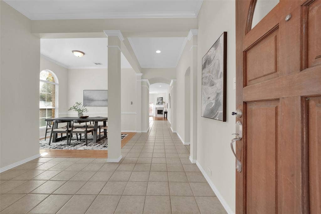 Wood-paneled entry door with chrome hardware opening to a tiled foyer