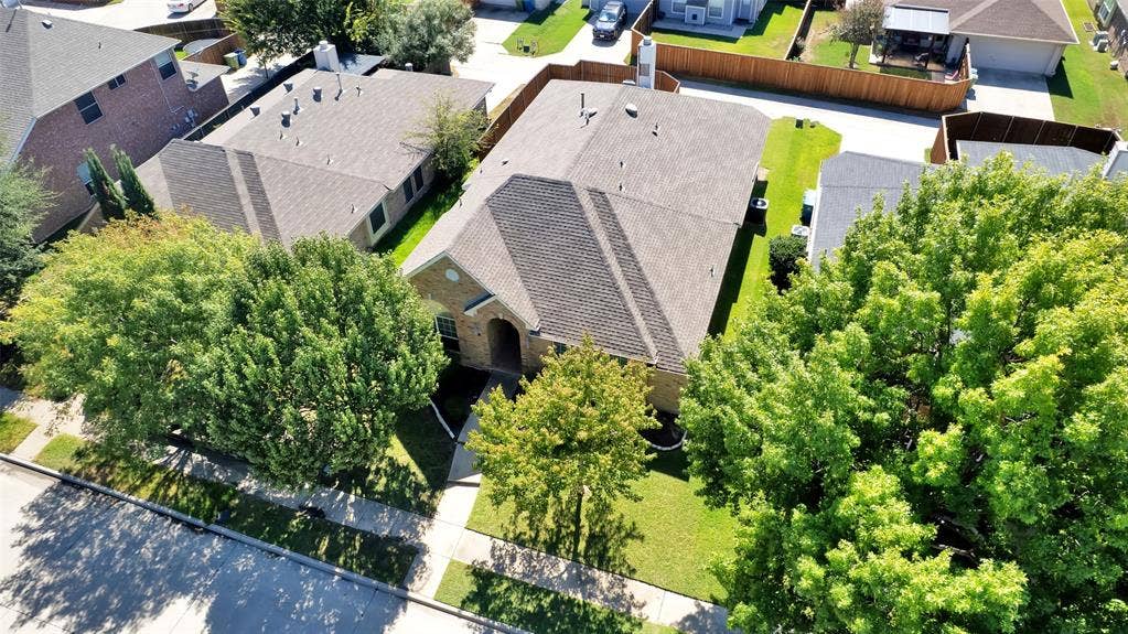 Traditional brick exterior with an arched entry, a gabled roof, a manicured lawn, and mature trees