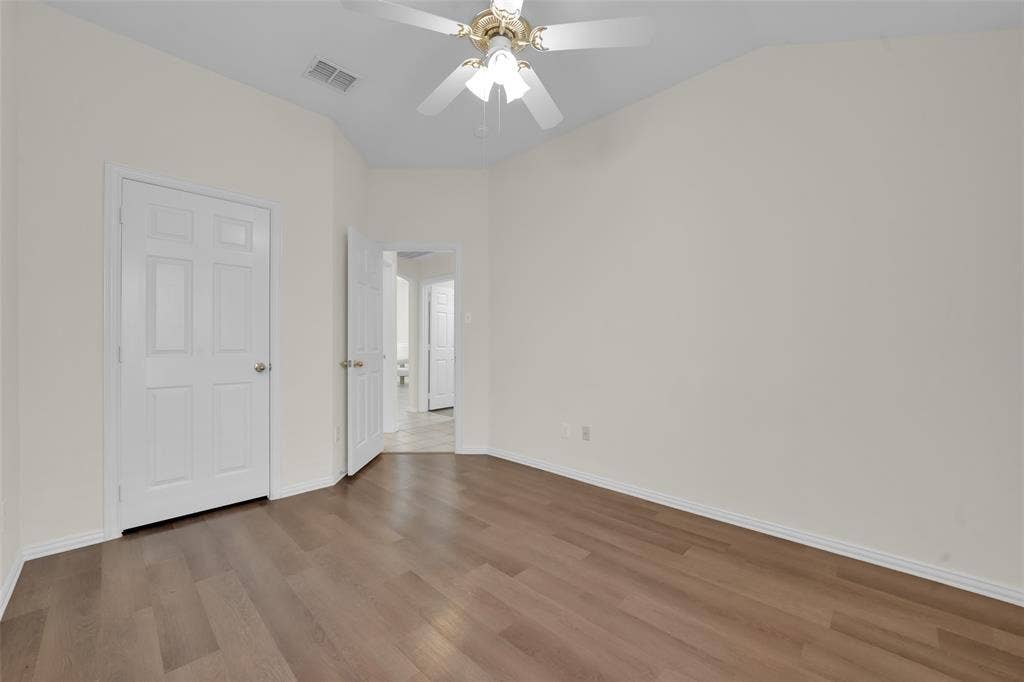 Vaulted ceiling with a ceiling fan, wood-finish flooring, and white paneled doors